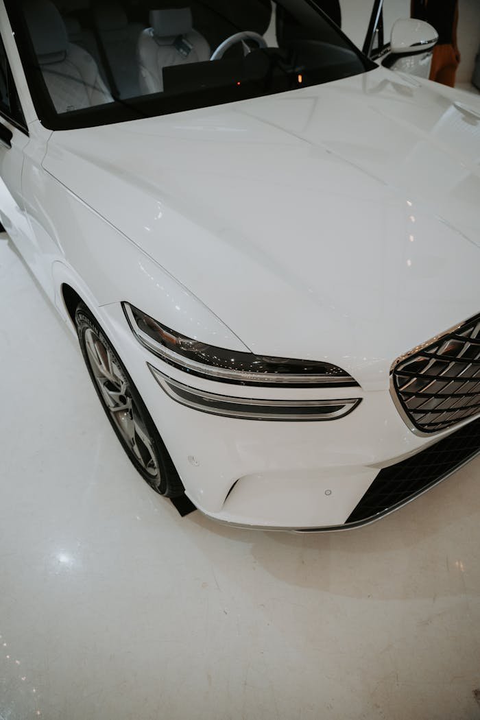 Sleek white luxury car showcased in a modern indoor showroom setting.